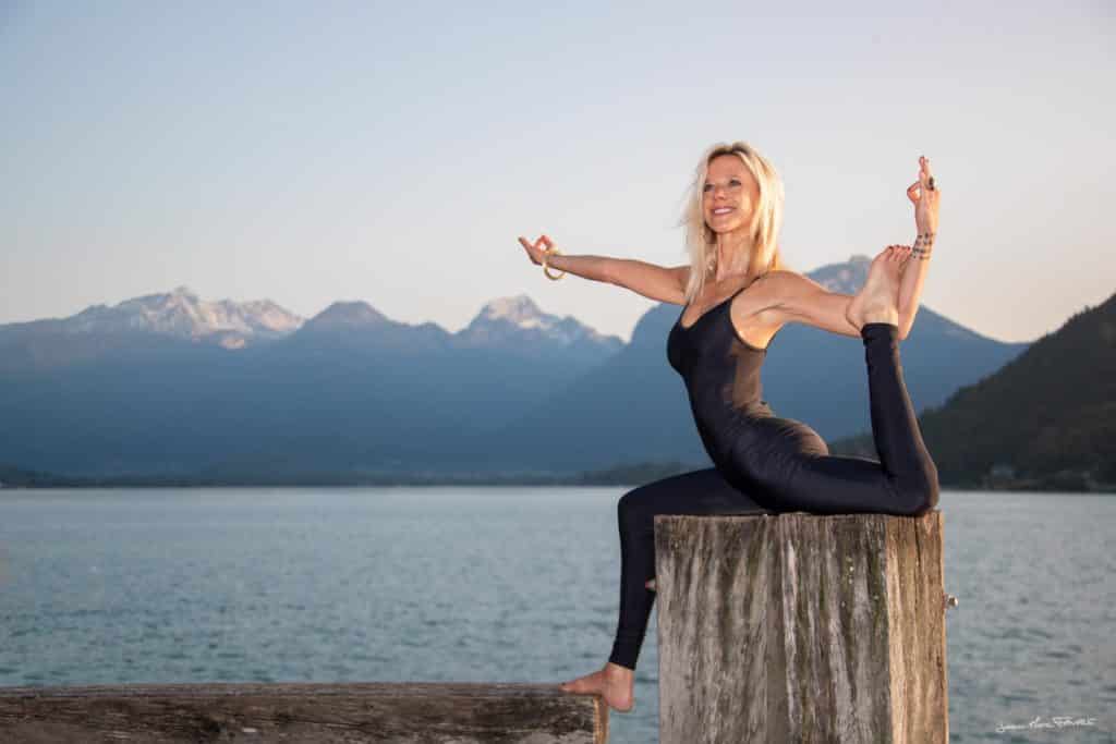 Femme en posture de yoga face au lac